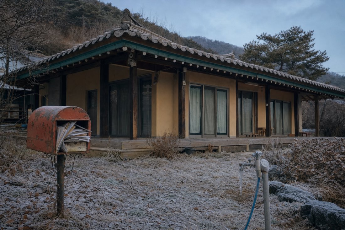 한겨울 비어 있는 전원주택 — 서리 낀 마당, 우편물이 쌓인 우편함, 처마의 고드름. 분위기를 보여 주는 예시 이미지